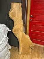 Full view of live edge plank front side leaning against cabinet and red door