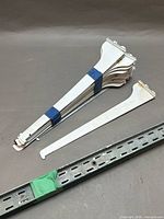 Bundle of white shelf brackets and one 4-ft slotted rail