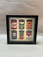 Front view of framed print showing six cans