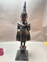 Full front view of carved wood Buddha on pedestal with scale can