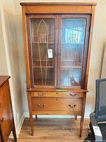 Full view of cabinet showing glass doors, drawers, legs