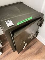 Exterior of vintage metal safe with door ajar showing lever handle and dial