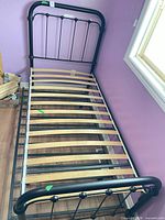 Full view of black metal trundle bed frame with wood slats