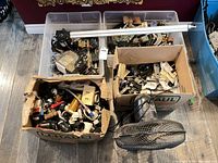 Overhead view showing two tubs and two boxes filled with electrical boards and plumbing fittings plus fan head and motor arm