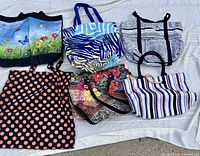 All six patterned fabric tote bags laid out on sheet