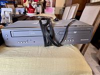 Front view showing DVD tray, VHS slot, buttons, branding, power cord