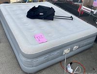 Full size raised inflatable air mattress with built-in pump, power cord, and black storage bag on top