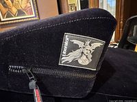 Close view of Liberator logo patch and zipper on black micro-suede cover