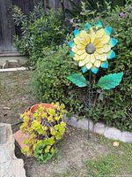 Sunflower stake and potted succulent displayed in garden setting