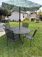 full patio set outdoors: table, four chairs, umbrella
