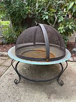 Full view of copper bowl fire pit on wrought iron stand with mesh screen