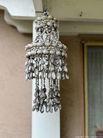 Full view of tiered seashell chandelier hanging outdoors