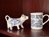 Cow creamer and scenic mug on shelf