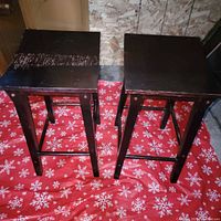 Two brown wooden bar stools on red cloth