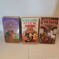 Front covers of three Robert Asprin Myth series paperbacks