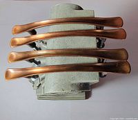 Four bronze drawer pulls stacked showing top view