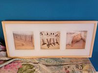 Front view of framed art showing three beach photographs in light wood frame with white mat