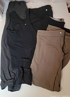 All five Lululemon items laid out: gray joggers, black top, black leggings, khaki leggings, green flares partially visible