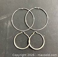 Both pairs of sterling silver hoop earrings displayed flat showing size difference