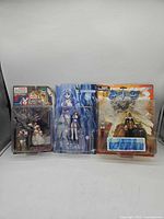 Three sealed action figures side by side in original blister packaging