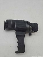 Side view of black 8x40 monocular with pistol grip and lens caps attached