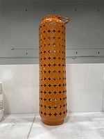Full view of tall orange cylindrical lantern candle holder