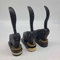 Three black cast iron seal embossers side by side showing overall form and quantity
