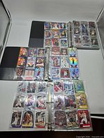 Three open binders showing pages of basketball cards