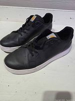 Left side view of pair of black Carhartt sneakers on white surface