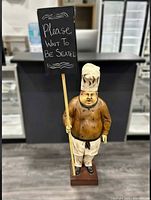 Full view of chef statue holding chalkboard