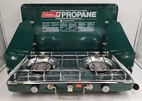 Stove open showing burners, grate, windshields, branding label