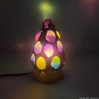 Lamp illuminated in dark environment showing multicolour glow through egg openings