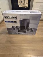 Front view of sealed Hauss HS-7 home theater system box displaying model, power rating, and system image