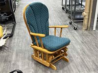 Front angle of wooden glider rocking chair showing upholstery and frame