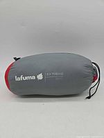 Rolled Lafuma Extreme 800 sleeping bag in gray/red stuff sack with logo visible