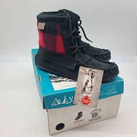 Pair of black suede moccasin booties on top of original box