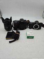 Full lot showing both camera bodies, lens, charger, boxed battery