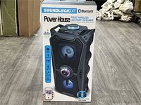 Front of sealed retail box showing speaker image and feature icons