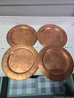Top view of four hammered copper charger plates