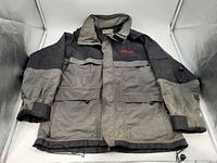 Front view of the two-tone Snap-On rain jacket showing zipper, storm flap, pockets, cuffs, embroidered logo