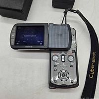 Camera open showing swivel LCD, strap, case, charger
