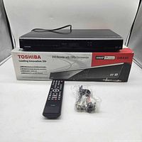 Front view of Toshiba DR430KU DVD recorder with remote, cables, and box