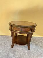 Front view of round end table showing drawer and lower shelf