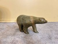 Left profile of green soapstone polar bear sculpture on carpeted floor