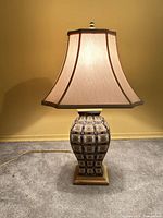 Lamp illuminated, showing patterned body, wood base, shade