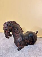 Front left view of hollow plaster Tang-style horse sculpture showing black surface with red highlights