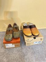 Both pairs of mules on original boxes showing colors and styles