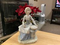 Front view of Tengra porcelain figurine showing woman, bonnet, basket of fish