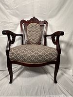 Front view of carved mahogany armchair showing upholstery and crest rail