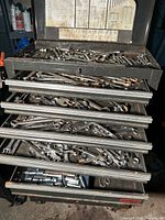 Open top toolbox and multiple drawers filled with combination wrenches and sockets